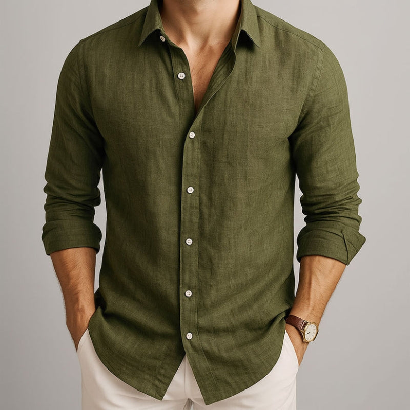 Man wearing a green button-up shirt with rolled-up sleeves on a neutral background and beige linen pants