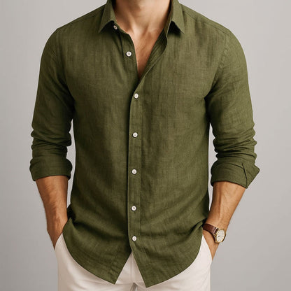 Man wearing a green button-up shirt with rolled-up sleeves on a neutral background and beige linen pants