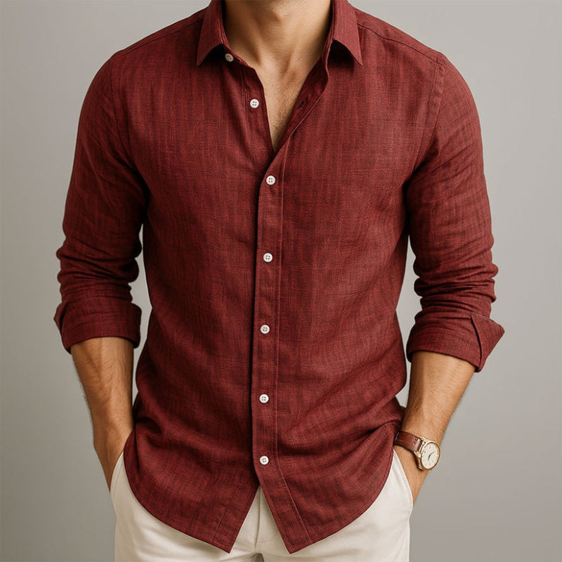 Man wearing a red button-up shirt with rolled-up sleeves on a neutral background and beige linen pants