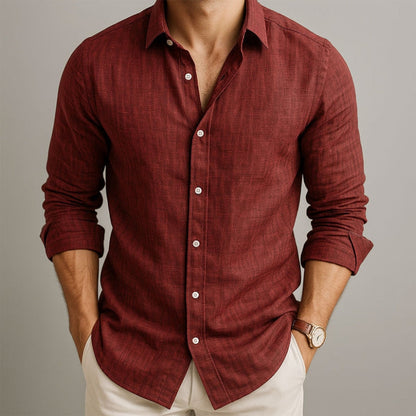 Man wearing a red button-up shirt with rolled-up sleeves on a neutral background and beige linen pants